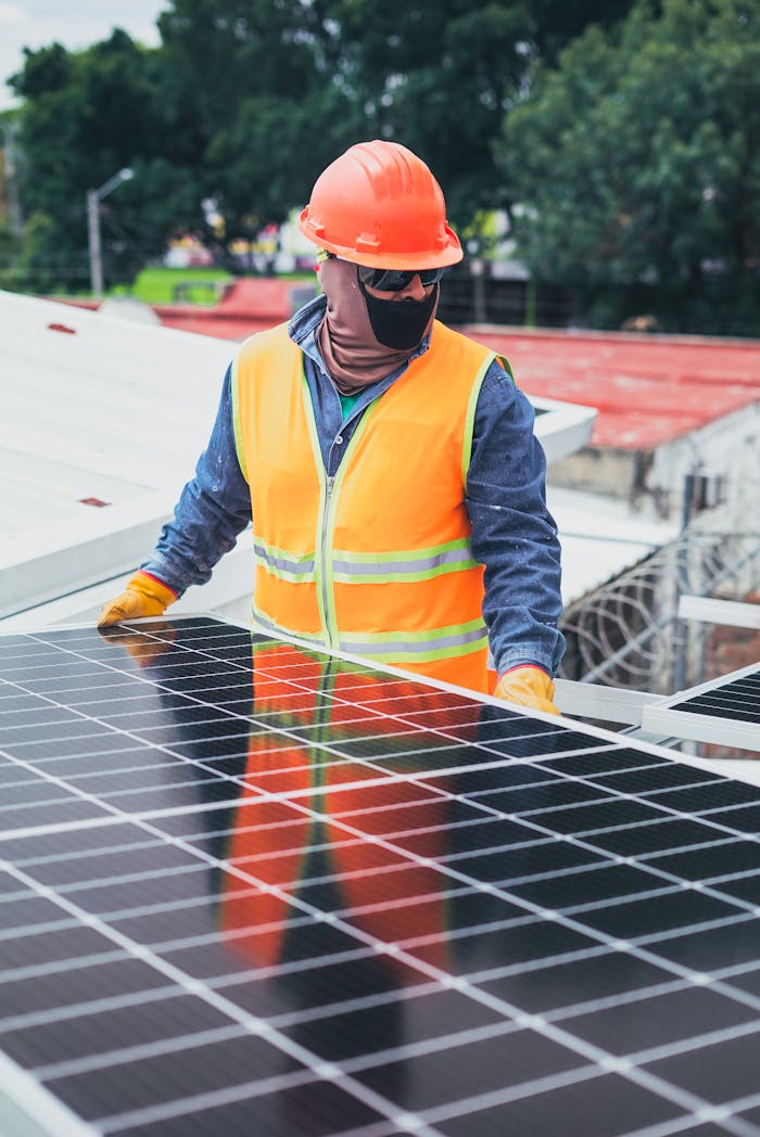 Technician in protective gear installing solar panels on a sunny day.