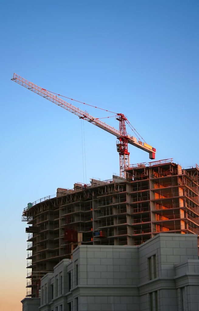 Tower crane on a high-rise building under construction at sunset, showcasing modern urban development.